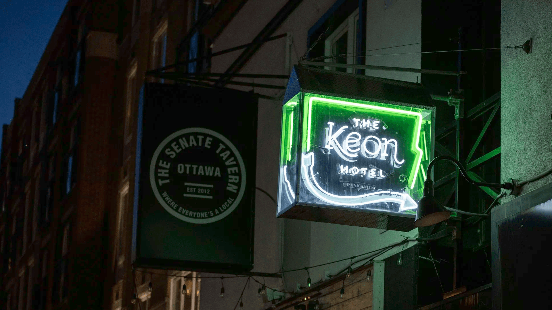 Neon signs for The Keon Hotel and The Senate Tavern illuminated at night.