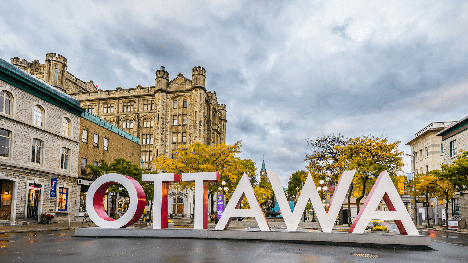 The iconic "OTTAWA" sign stands prominently amidst historic buildings and autumn foliage.