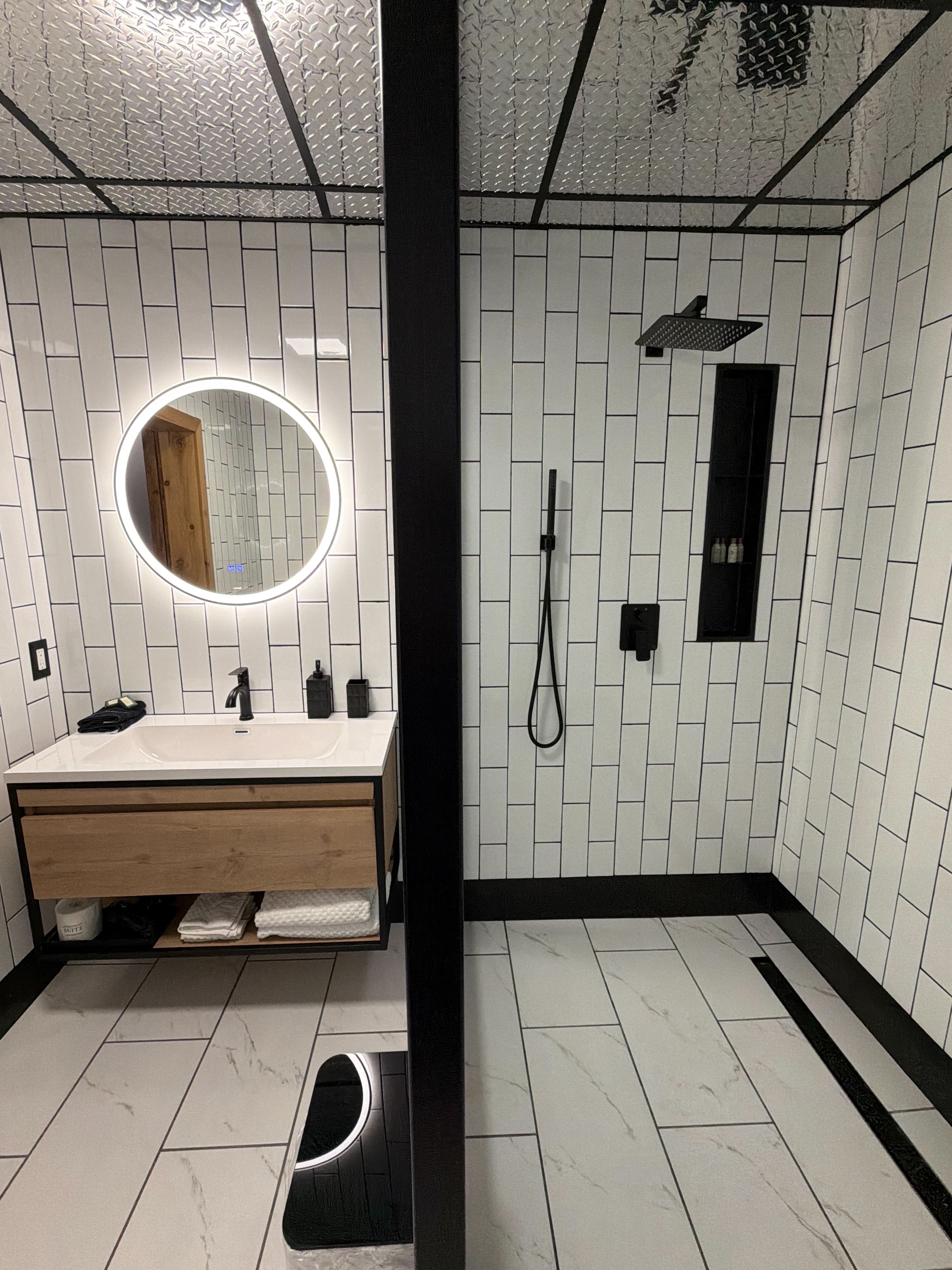 Modern bathroom featuring a round mirror, a sleek sink with wooden cabinetry, and a stylish shower area.