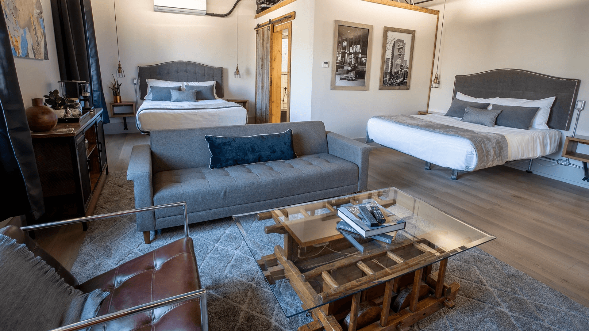 A stylish hotel room featuring two beds, a sofa, and a wooden coffee table.