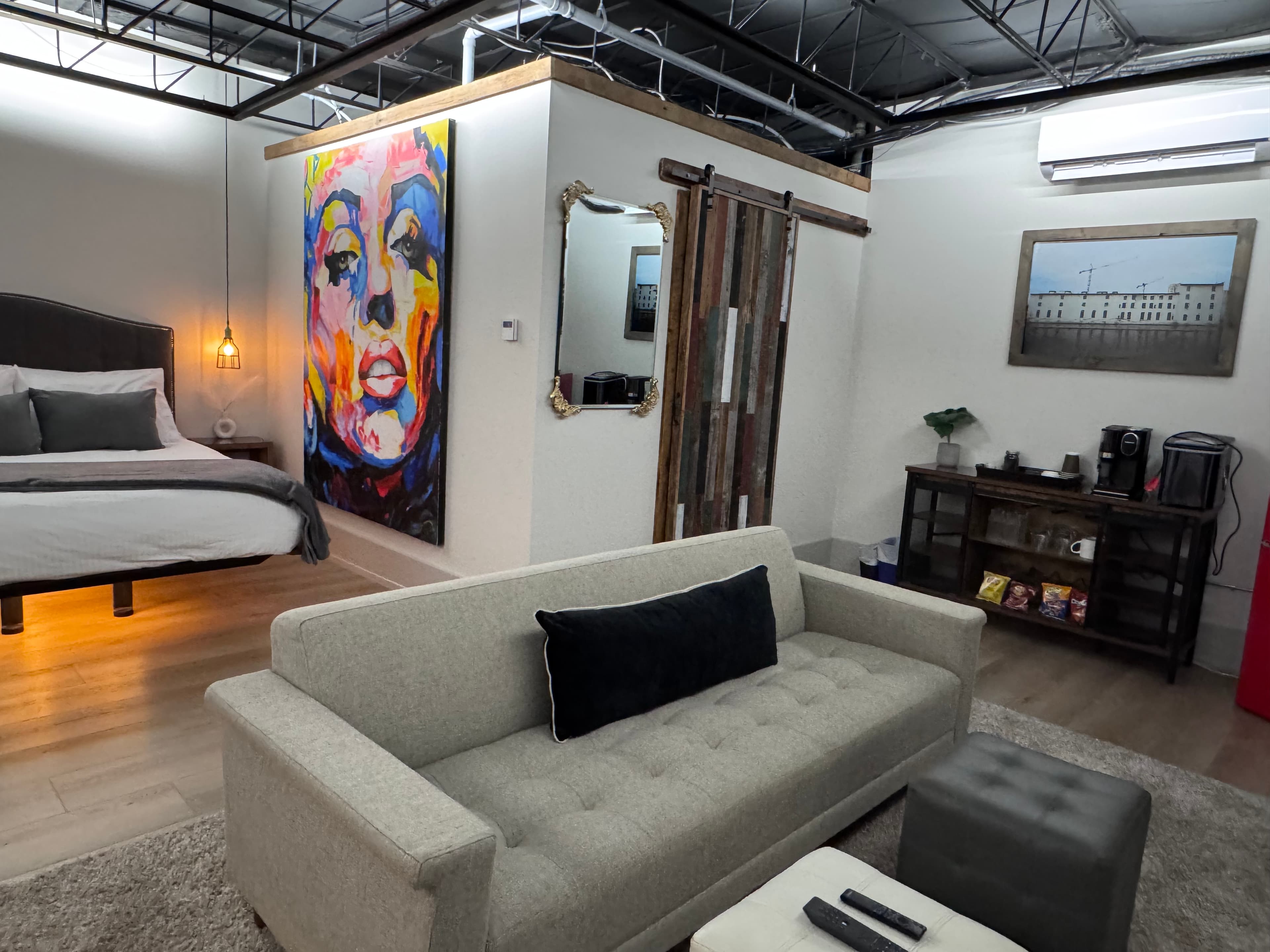 A cozy interior featuring a bed, colorful wall art, and a comfortable sofa set in a contemporary space.