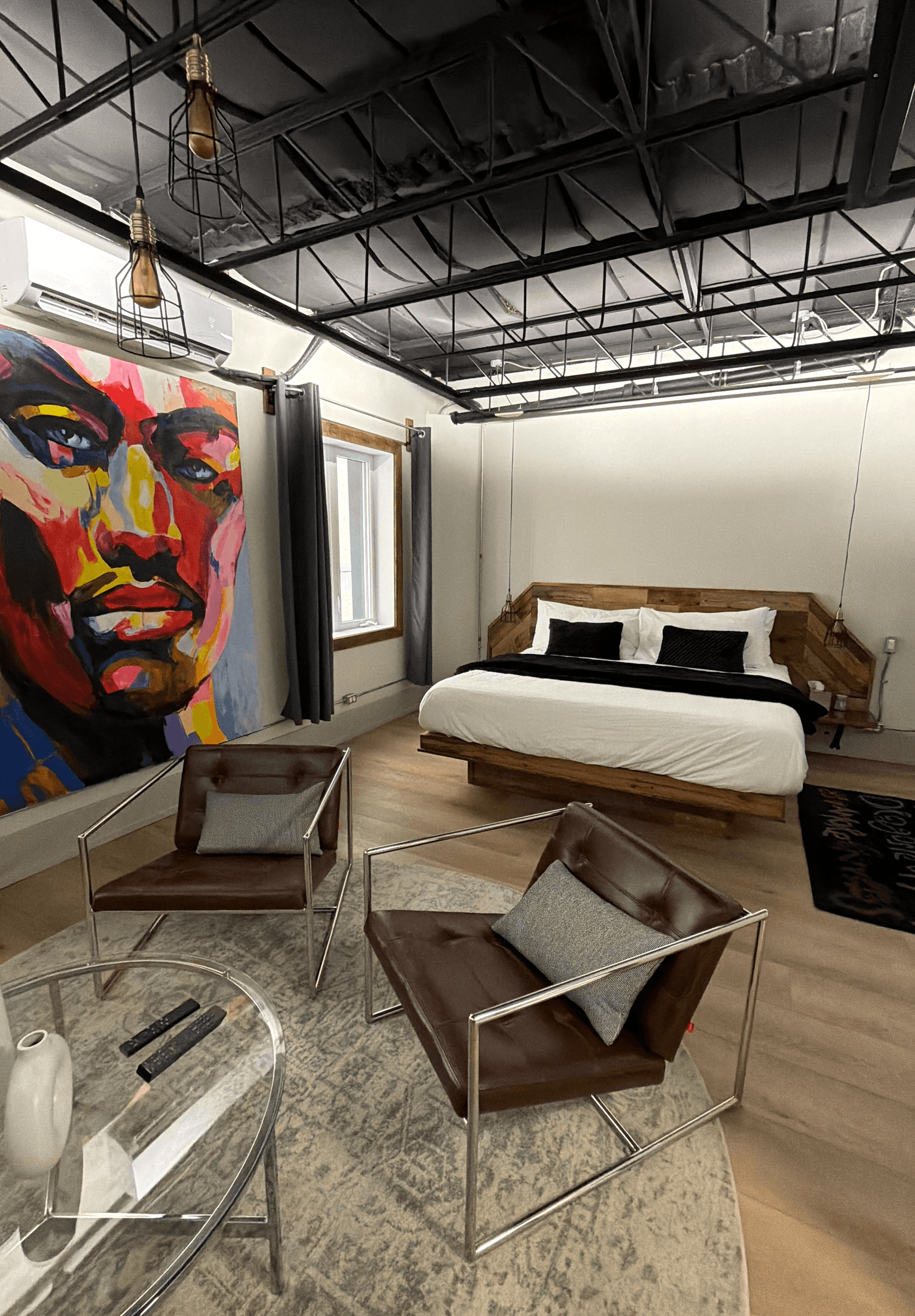 A modern bedroom featuring a large bed, colorful wall art, and stylish seating.