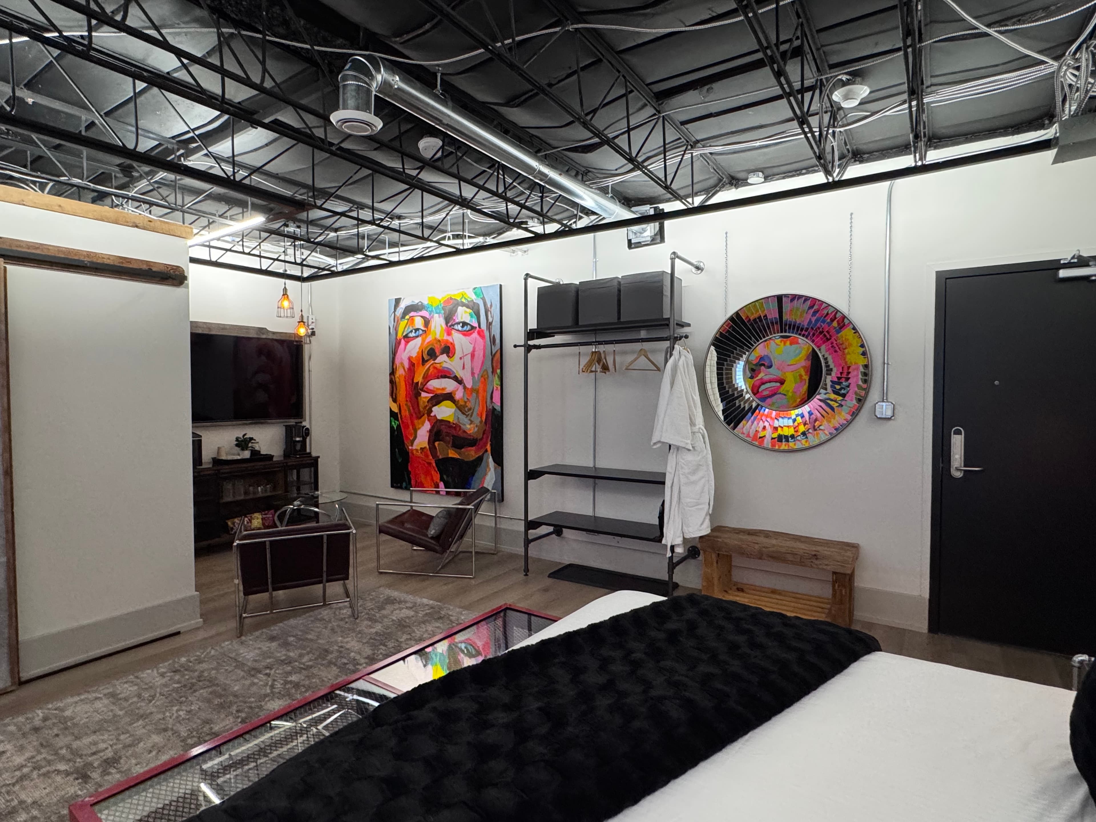 A stylish modern bedroom featuring colorful artwork, a television, and sleek furnishings.